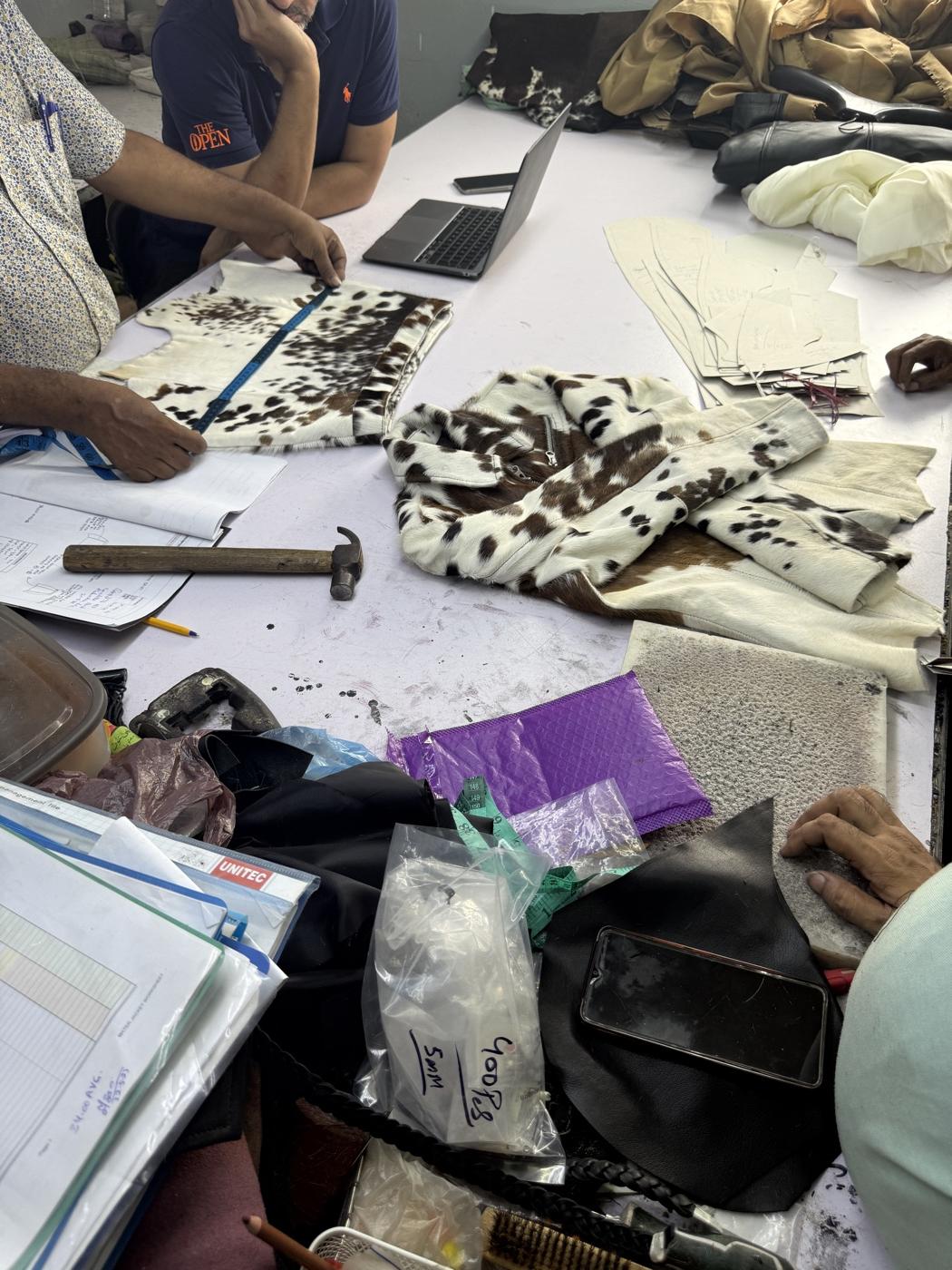 Cowhide leather samples and hardware components on design planning table
