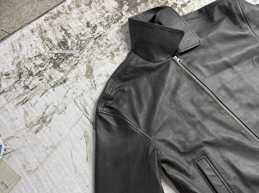 Finished black leather racer jacket laid flat on cutting table at Mac Leather factory