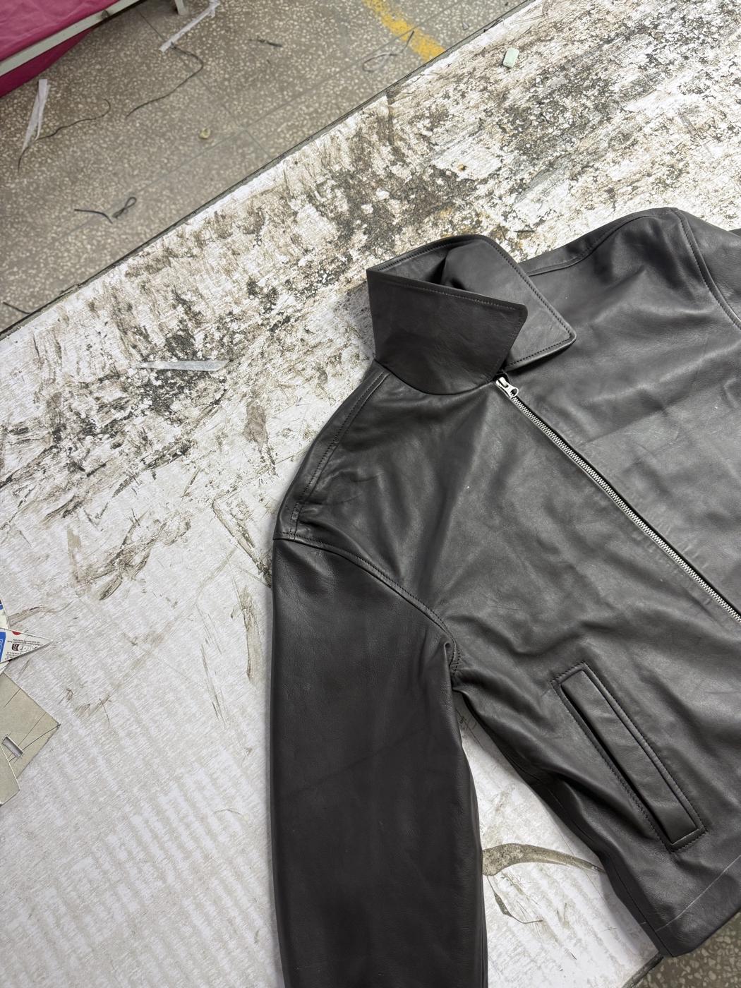 Finished black leather racer jacket laid flat on cutting table at Mac Leather factory