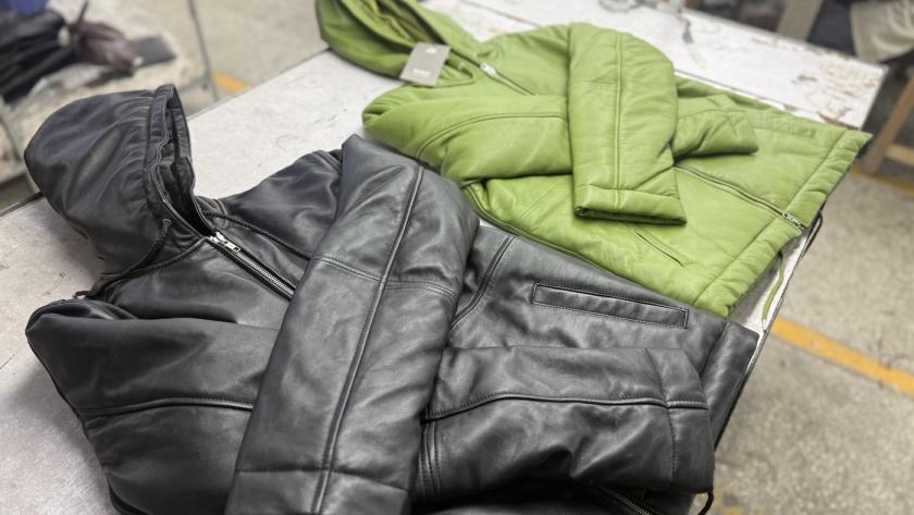 Finished leather bomber jackets in black and green with tags ready for shipping