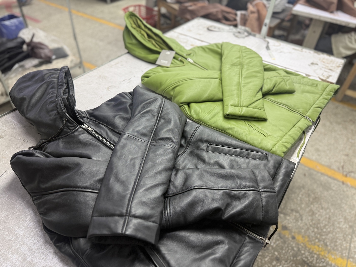 Finished leather bomber jackets in black and green with tags ready for shipping