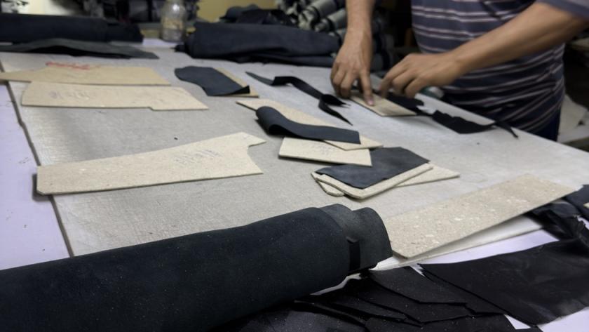 Leather cutter positioning pattern pieces on black sheepskin hide