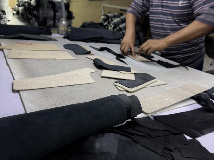 Leather cutter positioning pattern pieces on black sheepskin hide