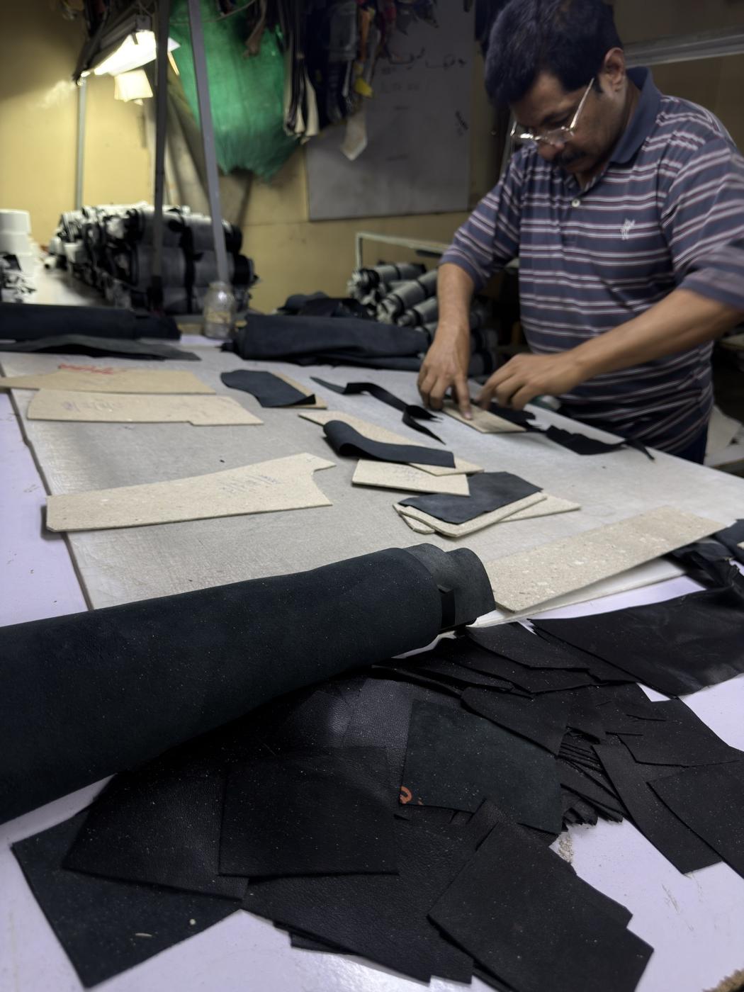 Leather cutter positioning pattern pieces on black sheepskin hide