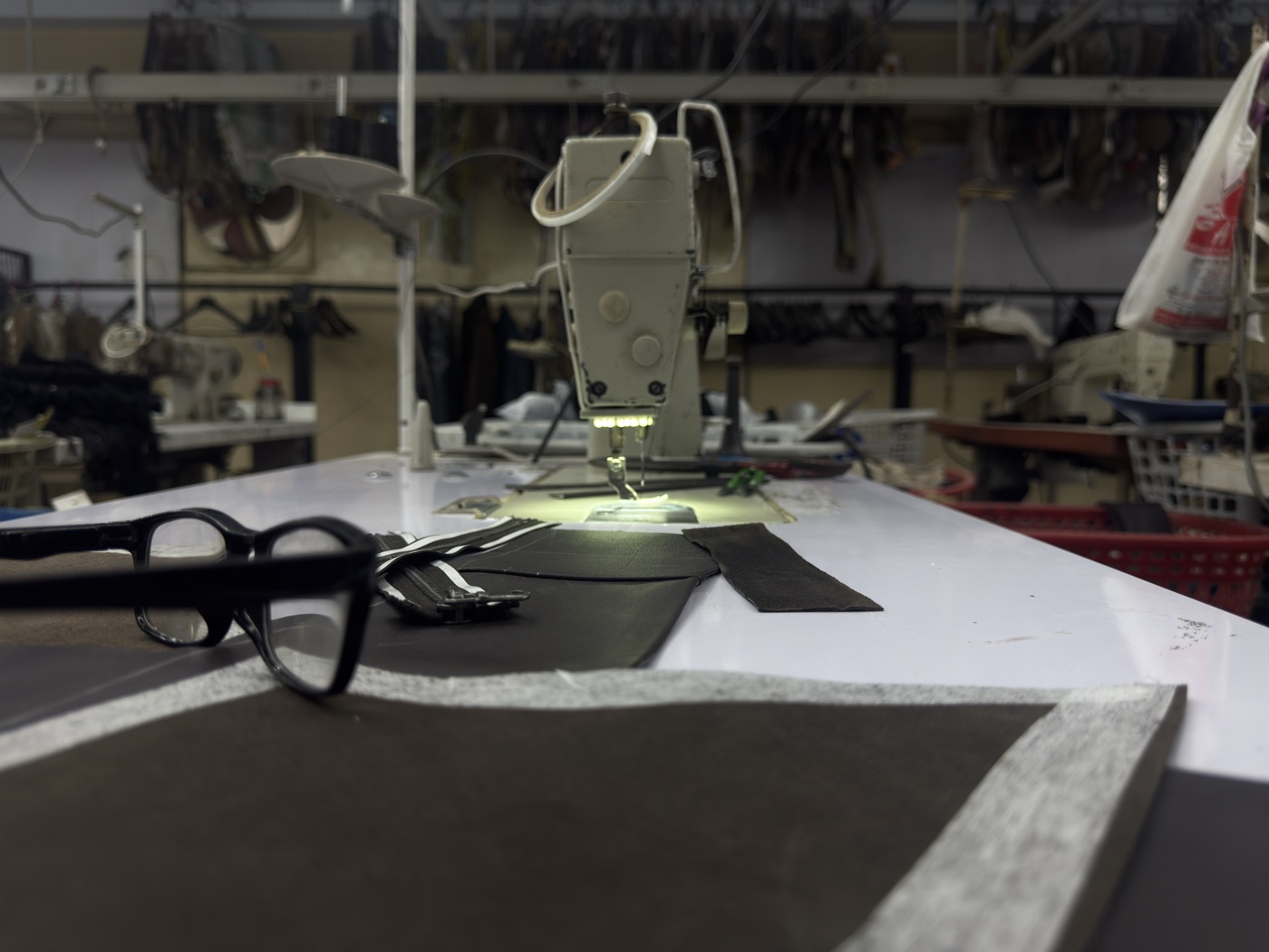 Sewing station with glasses leather pieces and industrial machine on factory floor