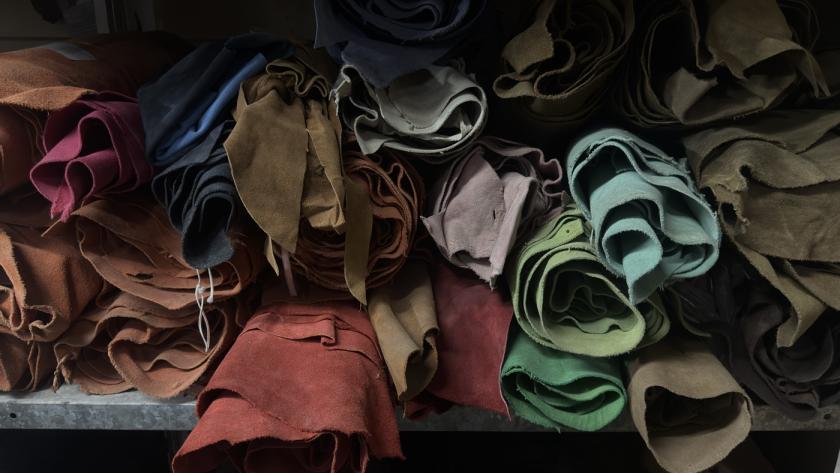 Rolled leather hides in multiple colours on storage shelves at Mac Leather