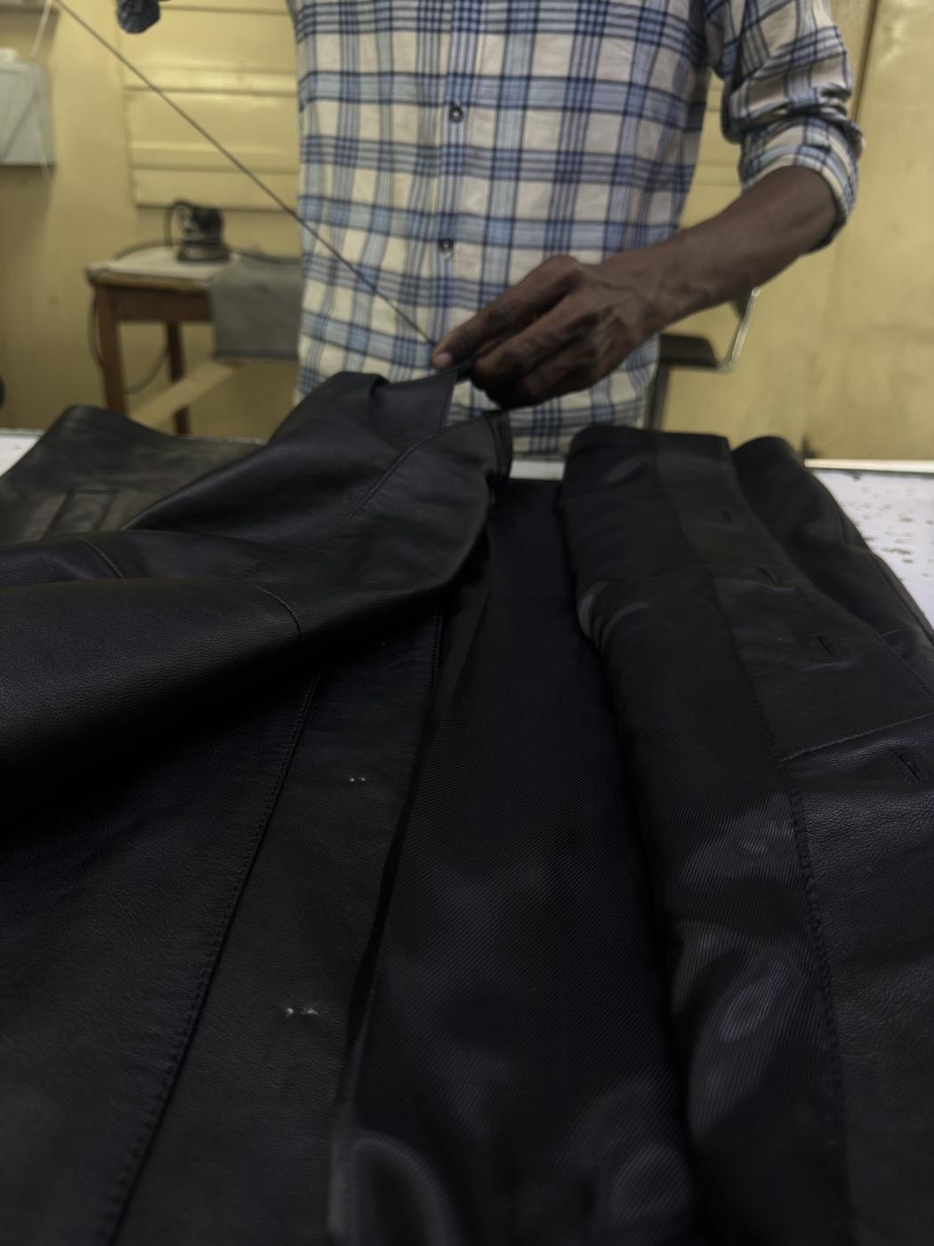 Quality control inspector examining finished black leather jacket at Mac Leather Karachi